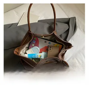 Macro view of large brown vintage tote bag showing spacious inner compartment and daily items