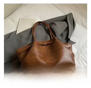 Detail of brown woven leather tote bag with elegant gold metal buckle and long handles