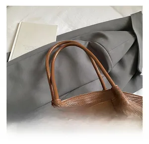 Detailed view of caramel brown woven leather tote with comfortable round handles