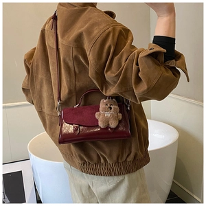 Detail der burgunderroten Tasche aus Wildleder und Lackleder mit Bärenanhänger