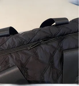 Détail du zip métallique fluide et de la broderie à nœuds sur le grand sac de sport noir