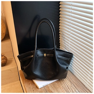 Detail of black woven texture tote bag with gold metal buckle on a wooden bench