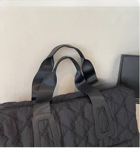 Détails des poignées renforcées et motifs nœuds brodés sur le sac fourre-tout noir