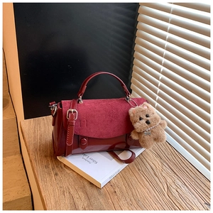Details der burgunderroten quadratischen Handtasche mit Leder-Patchwork und Welpen-Anhänger