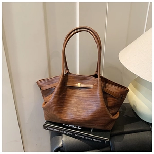 Detailed view of the brown textured leather tote bag on a black book with a warm lamp