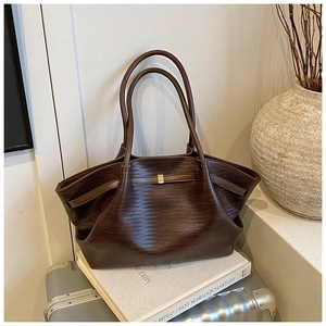 Close-up of dark brown woven leather tote bag with elegant golden hardware details