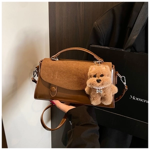 Detail einer braunen quadratischen Retro-Tasche mit Plüschhund-Anhänger und Texturmix