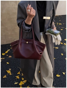 Detail of burgundy woven texture tote bag with gold buckle on autumn gingko background