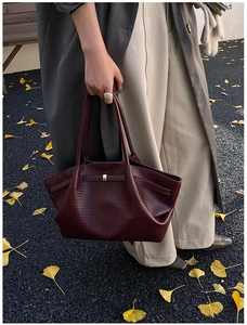 Close-up of deep red woven tote bag with pleated texture and golden metal buckle detail
