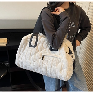 Vue détaillée du sac de voyage matelassé blanc avec broderie florale et anses noires