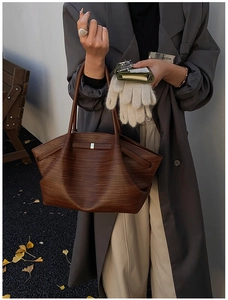 Detail of dark brown woven tote bag with textured surface and sleek metal buckle accents
