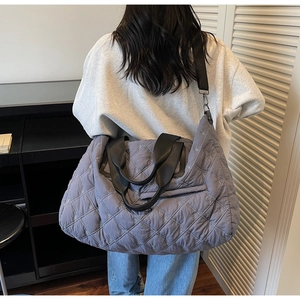 Sac cabas gris matelassé avec broderie de nœuds et double sangle porté par mannequin