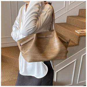 Detailed close-up of woven texture on khaki tote bag with elegant gold metal buckle