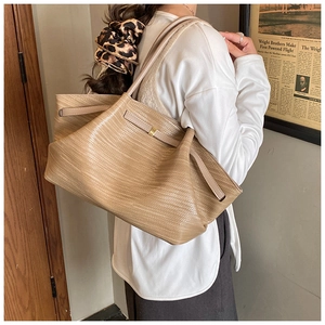 Close-up of the woven texture and golden buckle on the light brown tote bag