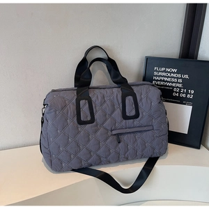 Détail du sac de voyage matelassé gris avec surpiqûres en losange et broderies fines