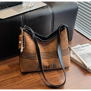 Detail view of brown suede tote bag with black trim and colorful wooden bead accessory