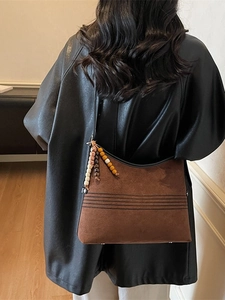Brown vintage suede tote bag with ethnic beaded charm shown on model's shoulder