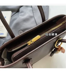 Close-up of smooth gold zipper and fine leather texture on brown crossbody bucket bag