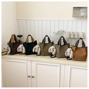 Borse a secchiello in cinque colori con charm a forma di coniglio in peluche su marmo bianco