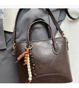 Detail view of dark brown leather crossbody bucket bag with decorative colorful wooden beads