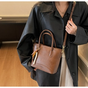Detailed macro view of retro brown faux leather shoulder bag with wooden beaded charm decoration