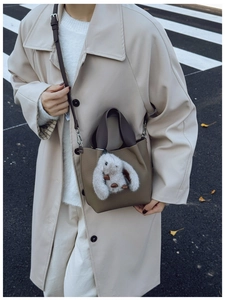 Borsa a secchiello marrone con texture litchi e ciondolo a coniglio in strada