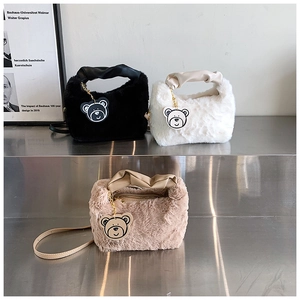 Dettaglio di borse in peluche nero bianco e kaki con ciondolo a forma di orso su scaffale