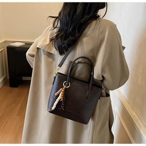 Detail of vintage brown bucket bag showing matte leather texture and beaded bag charm