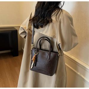 Detail of a dark brown vintage bucket bag with tassel charm and adjustable shoulder strap