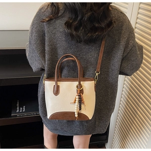 Detail of retro bucket bag featuring wooden beads tassel and contrast brown leather trim