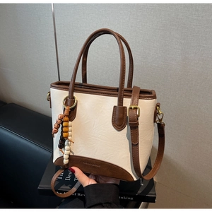 Detailed view of the retro bucket bag with wooden bead charm and gold buckle accents