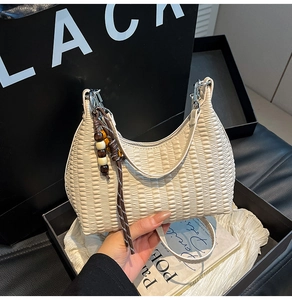 Detail view of cream pleated handbag featuring retro wooden bead tassel and textured fabric
