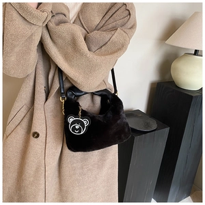 Détail d'un sac à main en peluche noire avec pendentif ours et bandoulière en cuir