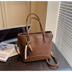 Close-up of retro brown bucket bag with lychee texture and beaded tassel detail