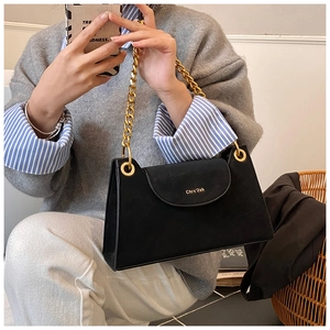 Detailed close-up of a black textured crossbody bag with a chunky gold chain and gold logo