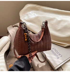 Close-up of brown woven hobo bag featuring decorative wood bead tassel and strap