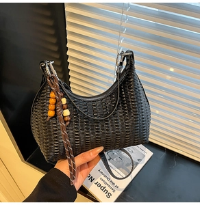 Detail of black pleated texture shoulder bag with wooden bead charm and silver zipper