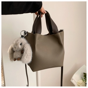 Dettaglio borsa a secchiello in pelle con texture litchi e ciondolo a forma di coniglio