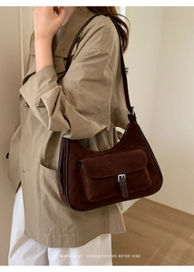Detailed side view of deep brown suede half-moon bag worn with a khaki trench coat