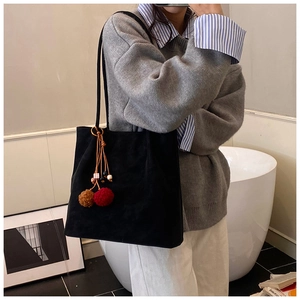 Detail van zwarte suède shopper met kleurrijke bedeltjes en slanke schouderbanden