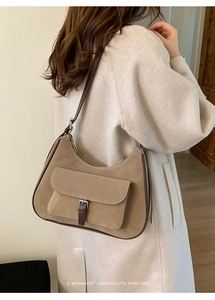 Brown vintage minimalist hobo bag in suede texture worn by model in a chic indoor setting