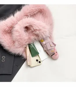 Dettaglio della borsa a tracolla in ecopelliccia rosa con smartphone e oggetti personali
