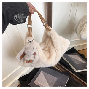 Dettaglio della borsa beige in peluche con tracolla in pelle marrone e ciondolo a coniglio