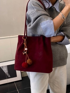 Donkerrode suède shopper met pompon hanger gedragen door een vrouwelijk model