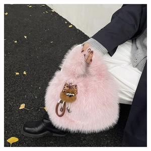 Borsa a secchiello in ecopelliccia rosa con ciondolo a orsetto su un cappotto scuro