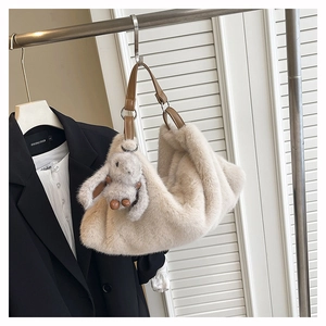 Dettaglio borsa a tracolla in peluche color crema con cinturino marrone e ciondolo a coniglio