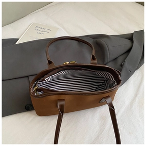 Details der braunen Vintage-Tasche mit gestreiftem Futter und goldenem Verschluss