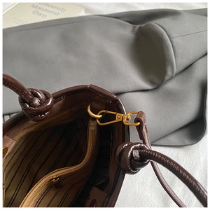 Détail de la quincaillerie dorée, doublure rayée et poignée nouée sur sac en cuir