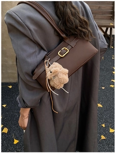 Detail der dunkelbraunen matten Schultertasche mit Goldschnalle und Plüschhasen