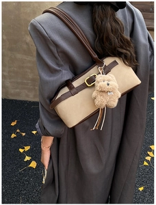 Detail der beige Retro-Schultertasche mit braunem Rand und süßem Teddybär-Anhänger